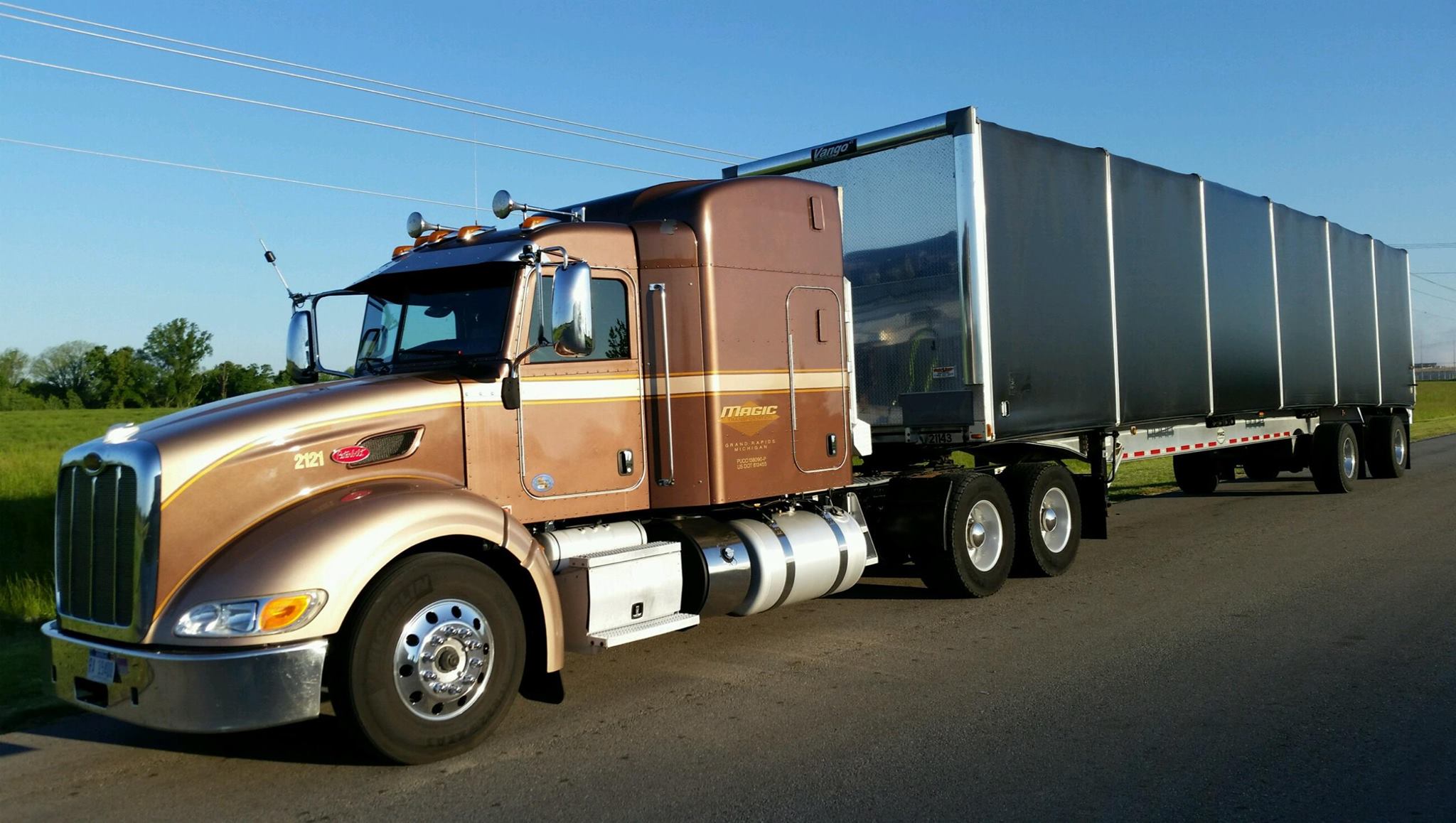 680f8650bb5d5_FLATCONESTOGA A semi truck with its trailer parked on the side of the road.