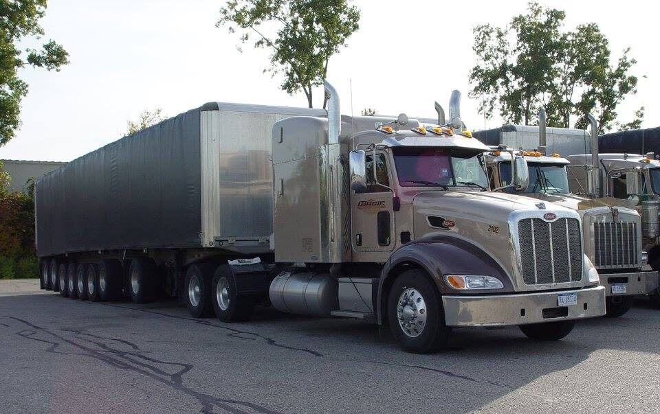 A semi truck parked in the parking lot of a building.